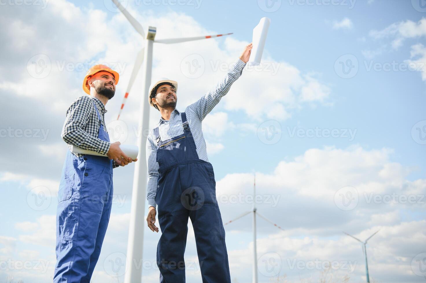 två ingenjörer diskuterar mot turbiner på vind turbin odla. foto
