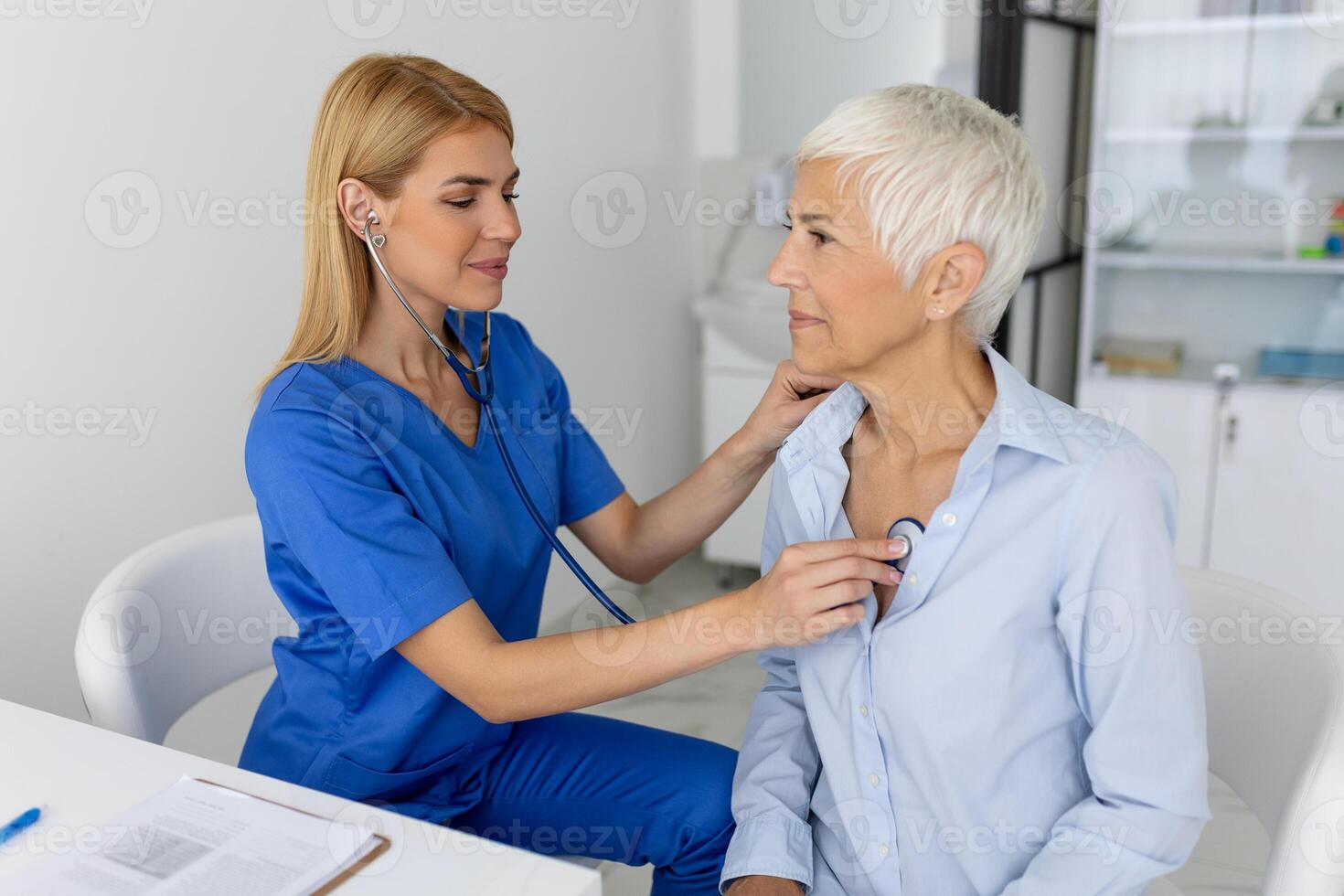 ung kvinna läkare lyssna till senior patient hjärta bröst med stetoskop på klinik möte. kvinna gp kolla upp undersöka kvinna klient med telefonndoskop. sjukvård begrepp. foto