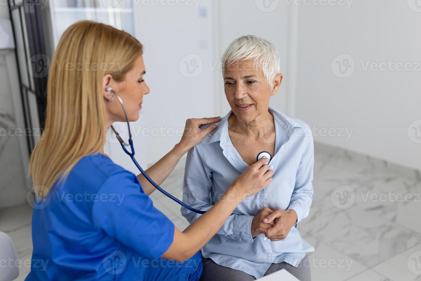 omtänksam kvinna läkare använda sig av phonendoscope undersöka senior patient hjärta Betygsätta på samråd i sjukhus. kvinna sjuksköterska eller gp använda sig av stetoskop lyssna till kvinnas hjärtslag i klinik. foto