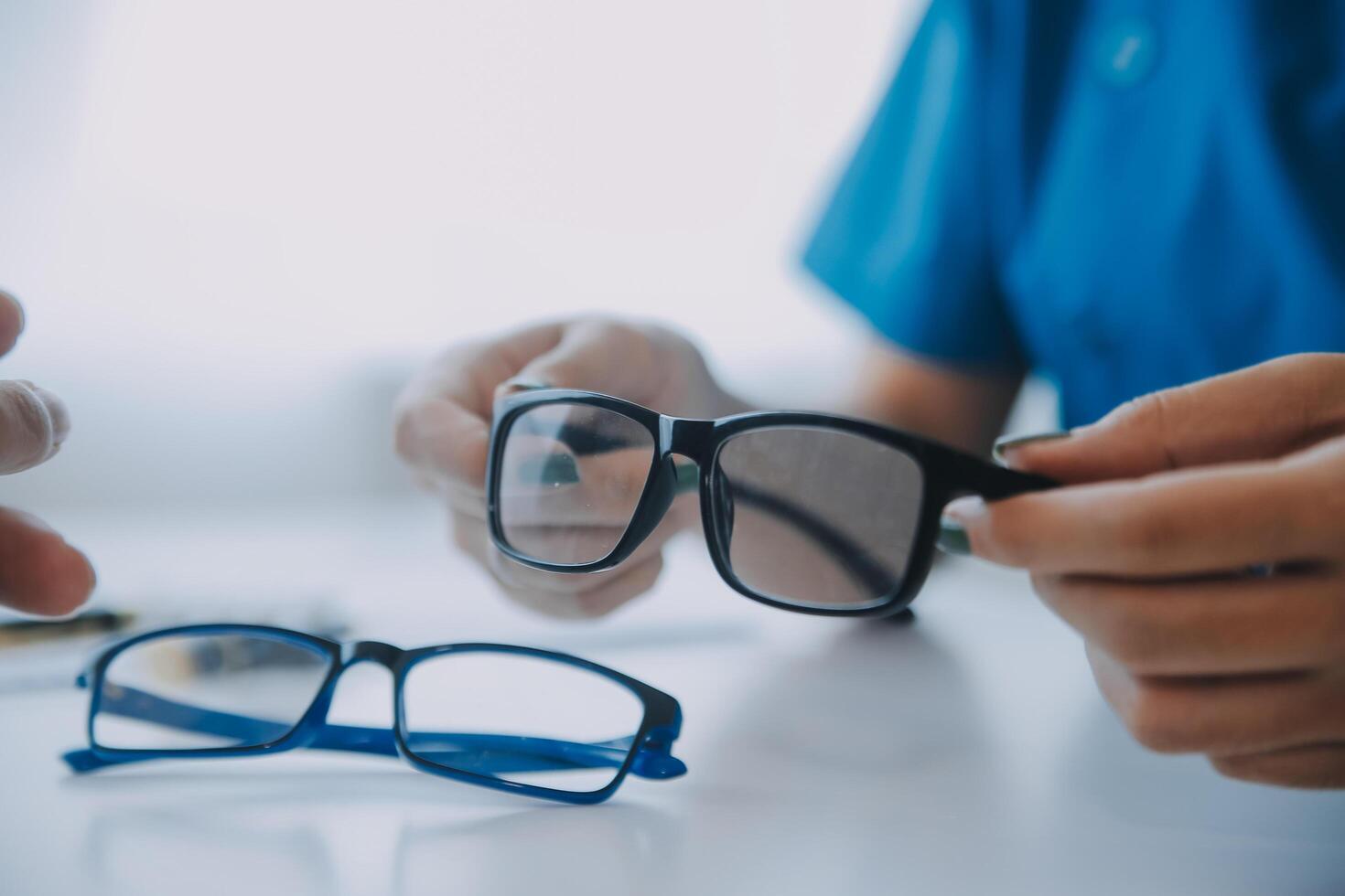 närbild av asiatisk kvinna läkare talande med äldre patient som visar eyeball modell och förklara öga sjukdom i sjukhus foto