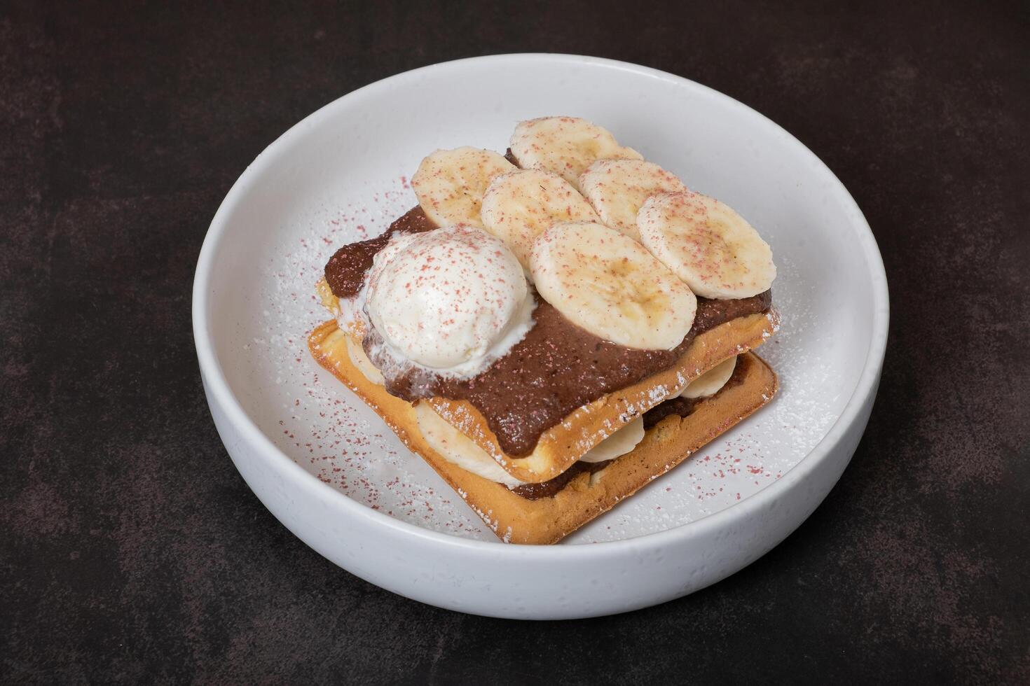 belgisk våfflor med banan och choklad sås på en mörk bakgrund foto