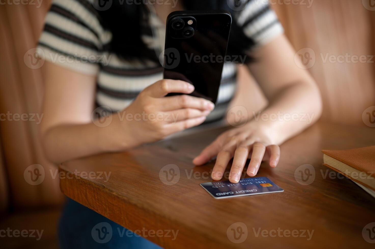 en kvinna registrerar henne kreditera kort på en handla app på henne mobil telefon, Sammanträde i en Kafé. foto