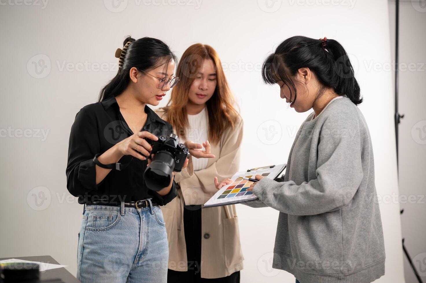 en professionell asiatisk kvinna fotograf talande med assistenter, framställning innan en skytte. foto