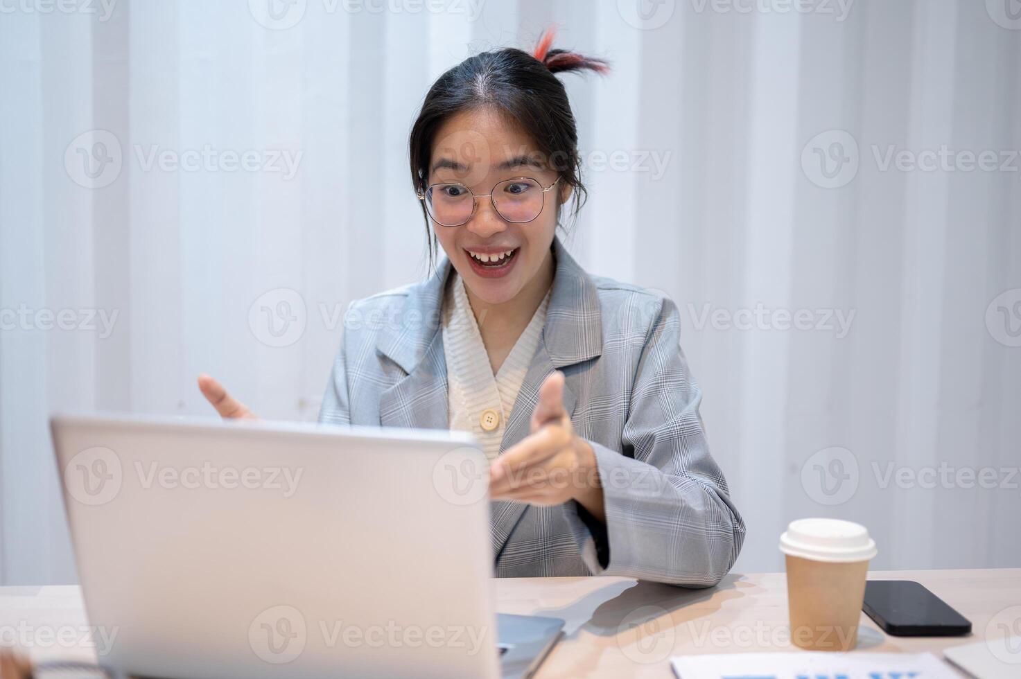 ett upphetsad asiatisk affärskvinna tar emot Bra Nyheter under ett uppkopplad möte med henne team. foto