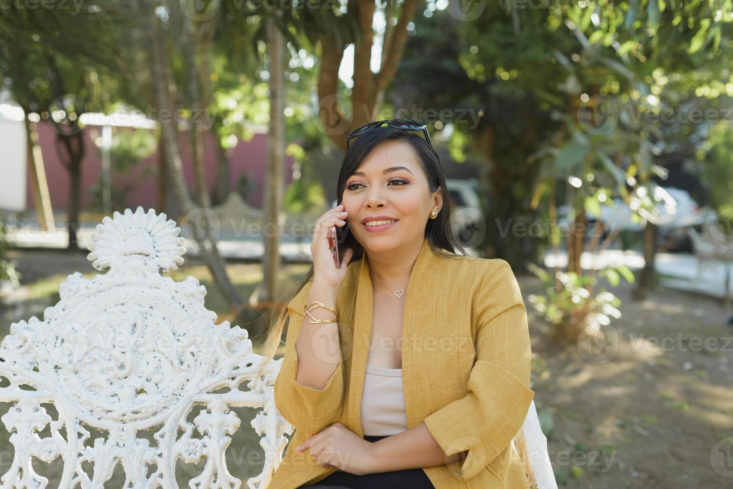 kvinna sittande på en parkera bänk talande på de telefon. solig dag. foto