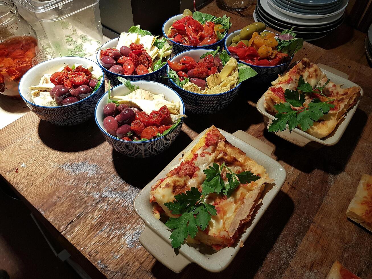 kronärtskockor, körsbär tomater och oliver med oliv olja och sallad och vegetarian lasagne. foto