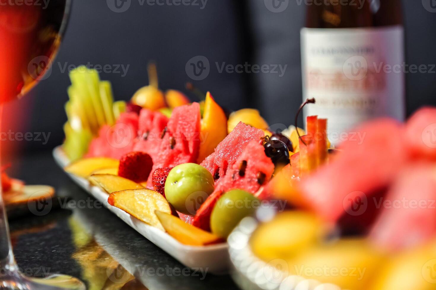 tallrik av blandad frukt och glas av röd vin foto