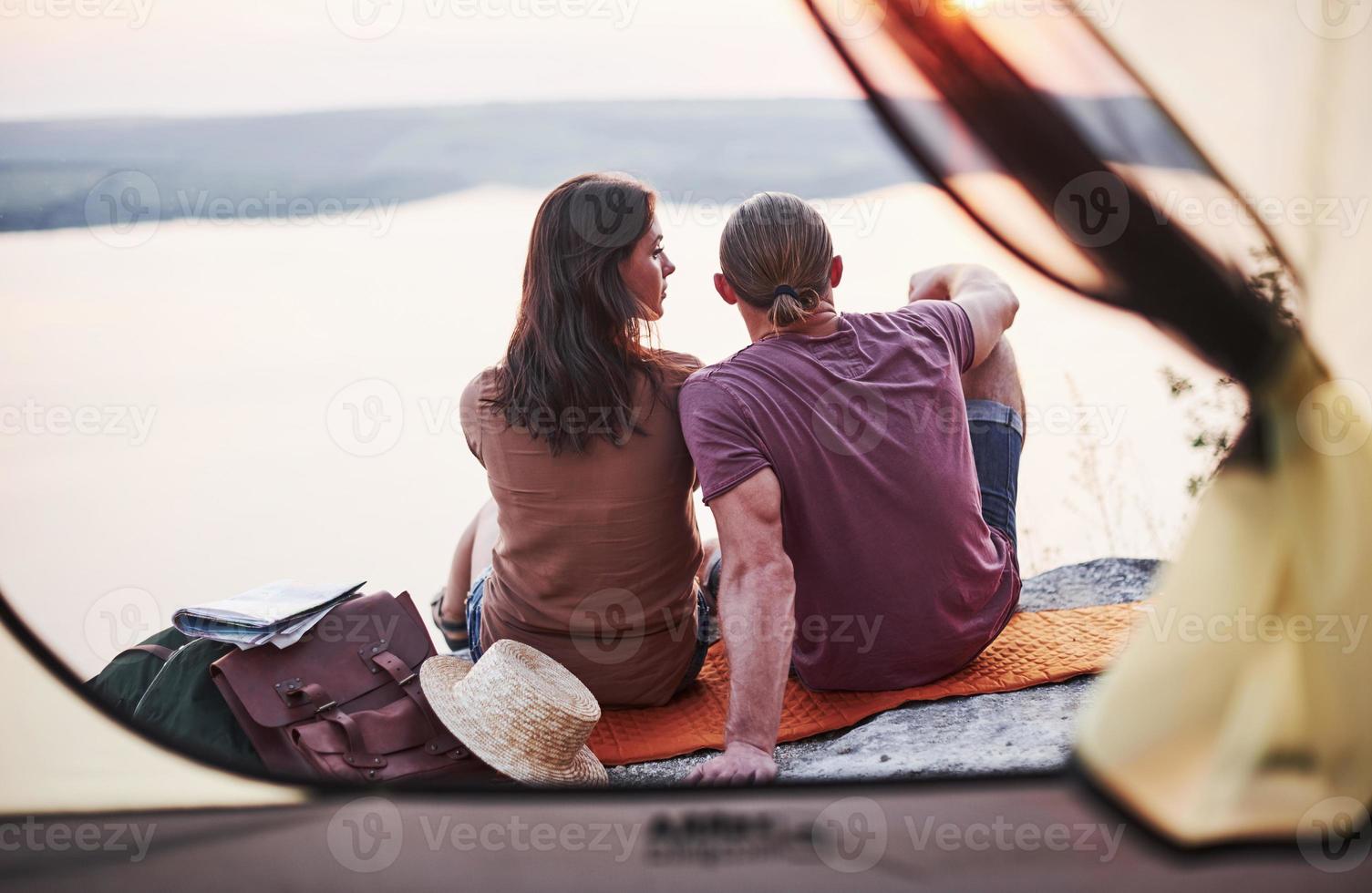 utsikt från tältet. två personer som sitter på klippan och tittar på vacker natur foto