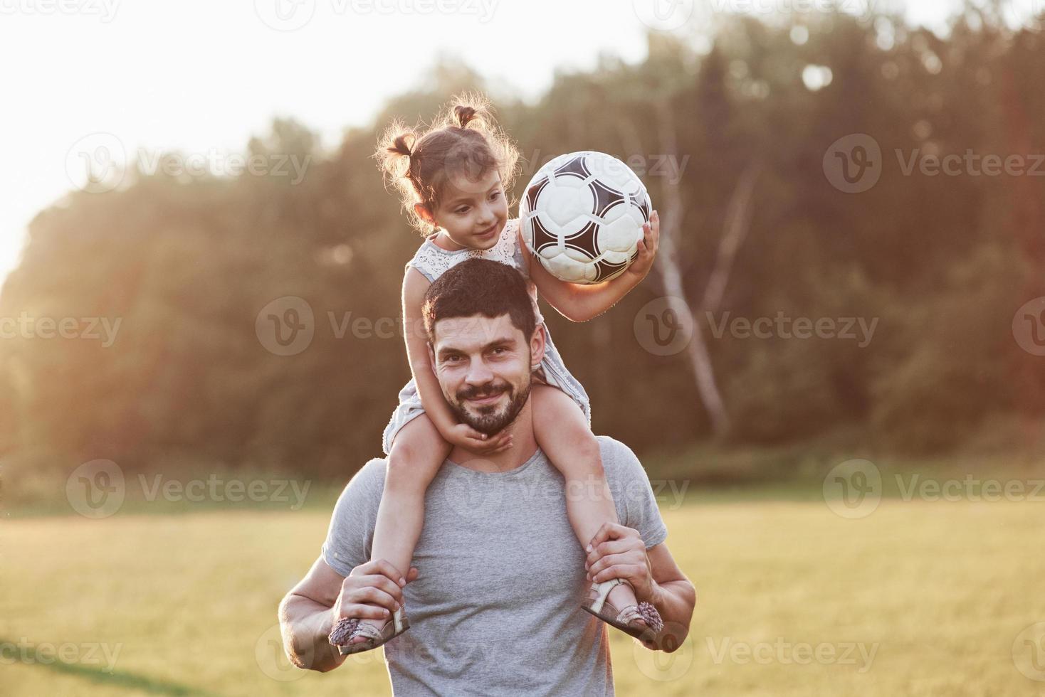 ren lycka. foto av pappa med sin dotter vid vackert gräs och skog i bakgrunden