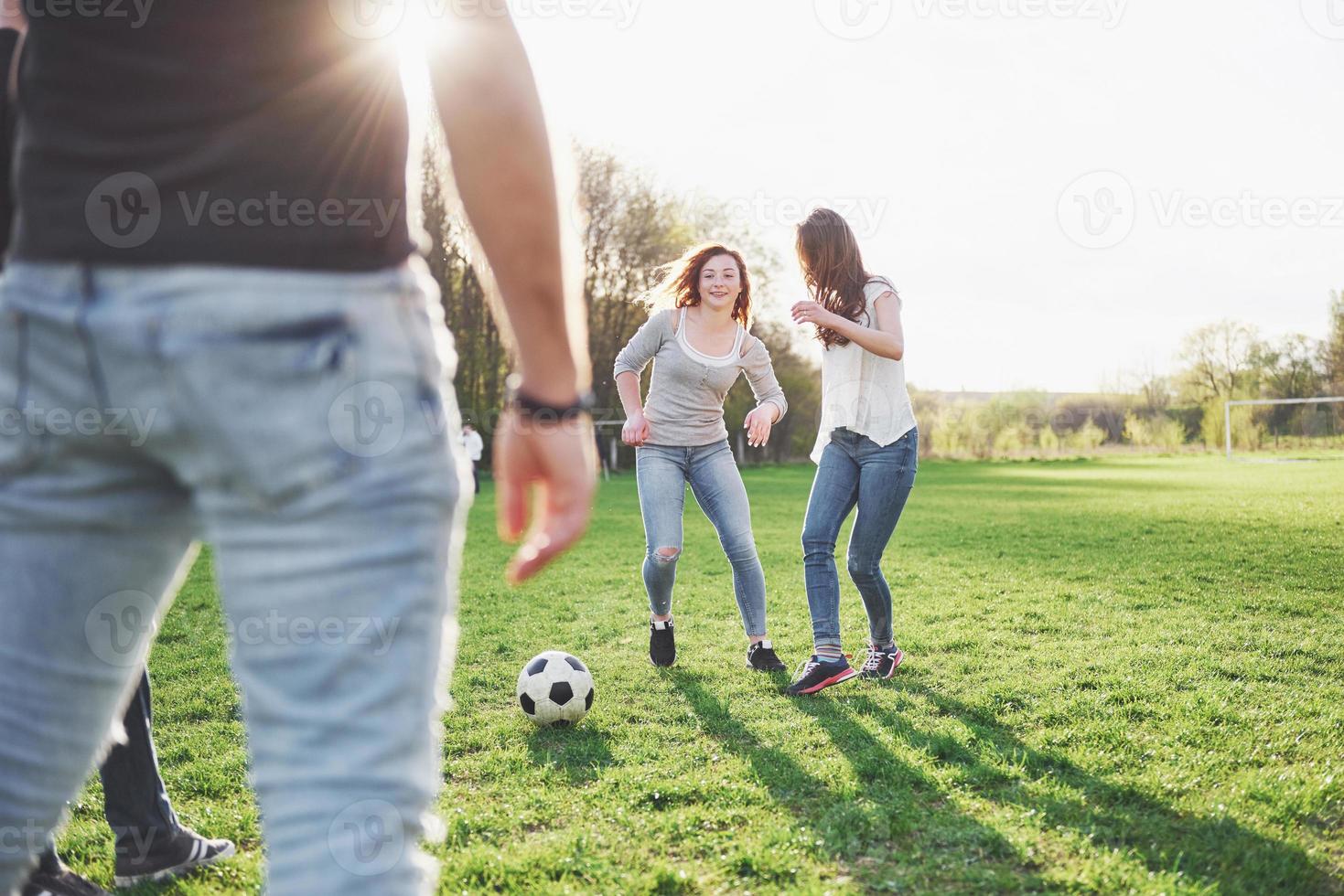 en grupp vänner i ledig outfit spelar fotboll utomhus. folk har kul och har kul. aktiv vila och vacker solnedgång foto