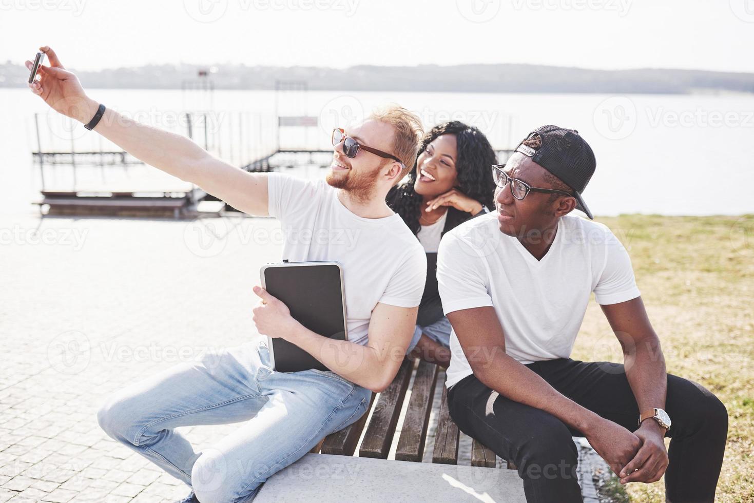 vackra multietniska vänner som använder en bärbar dator på gatan och gör selphie. ungdomens livsstilskoncept foto