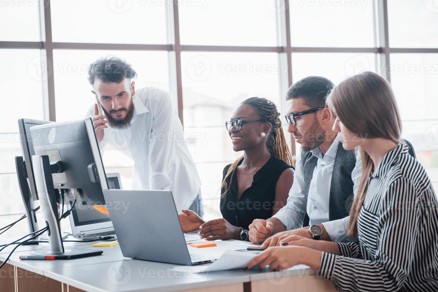 unga anställda sitter på kontoret vid bordet och använder en bärbar dator, ett teamwork brainstorming möteskoncept. foto