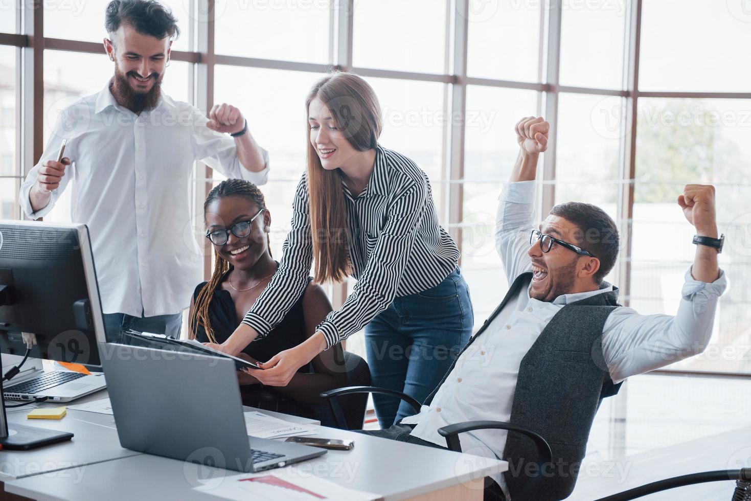 unga anställda sitter på kontoret vid bordet och använder en bärbar dator, ett teamwork brainstorming möteskoncept. foto