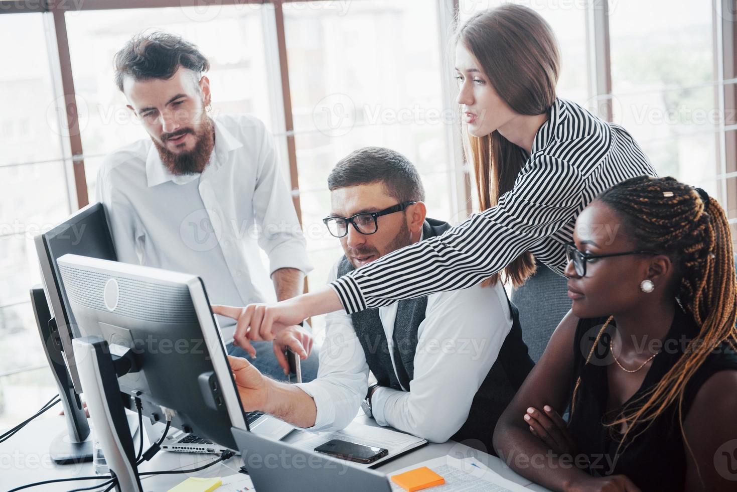 unga anställda sitter på kontoret vid bordet och använder en bärbar dator, ett teamwork brainstorming möteskoncept. foto