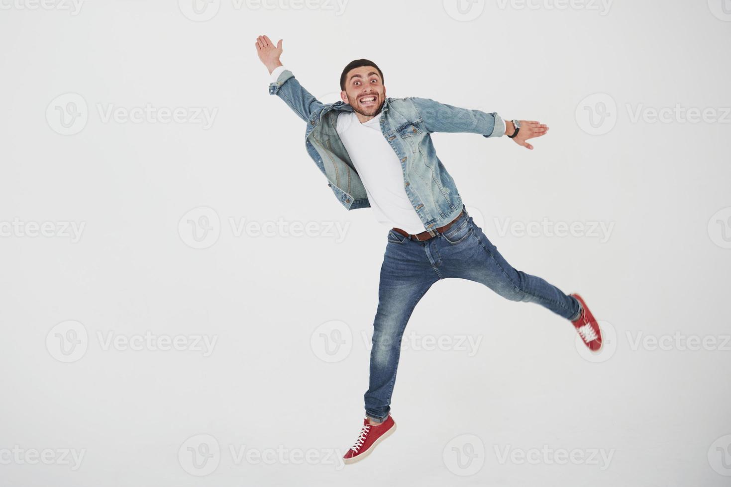 bild av glad ung man casual klädd hoppa över vit bakgrund göra olika gest foto