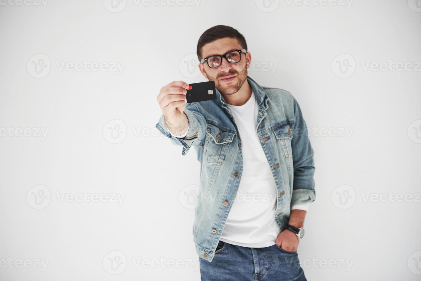ung stilig manlig företagsledare i ledig klädsel med ett kreditkort i fickorna på en vit bakgrund. konceptet med handel på internet och lättheten med elektroniska pengar foto