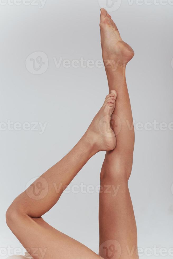 långsamt rörande. foto av kvinnliga smala ben upphöjda inomhus på den vita bakgrunden
