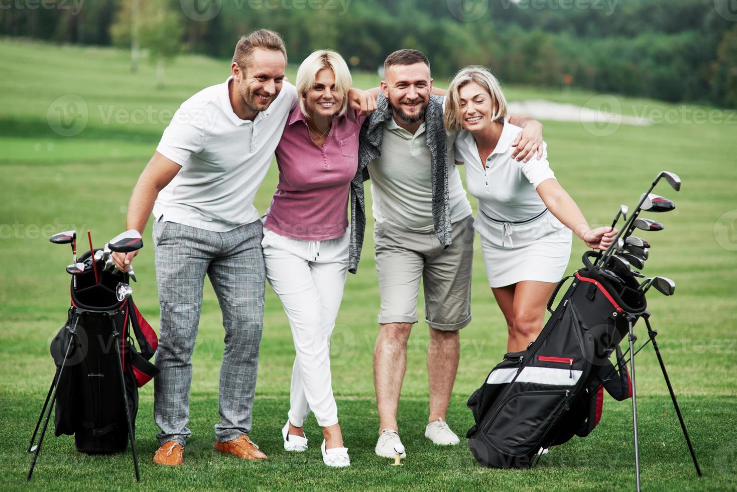 vackra skogar i bakgrunden. foto av vänner som kramas och ler med golfutrustning efter matchen