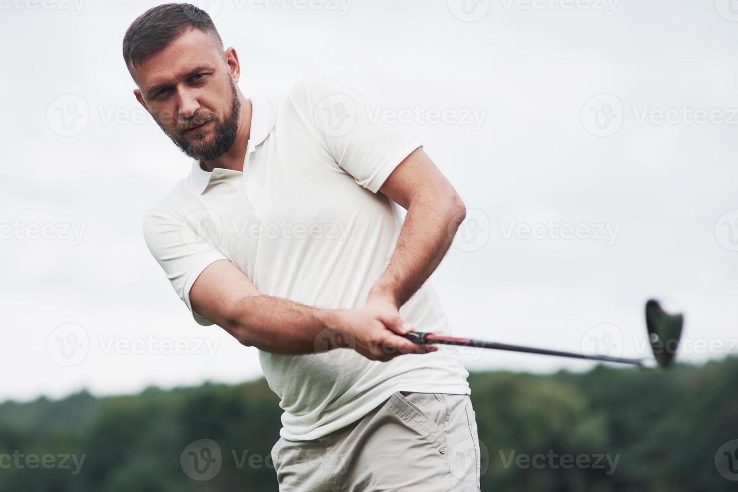 fokuserad blick. porträtt av golfspelare i gräsmattan och sticka i handen foto