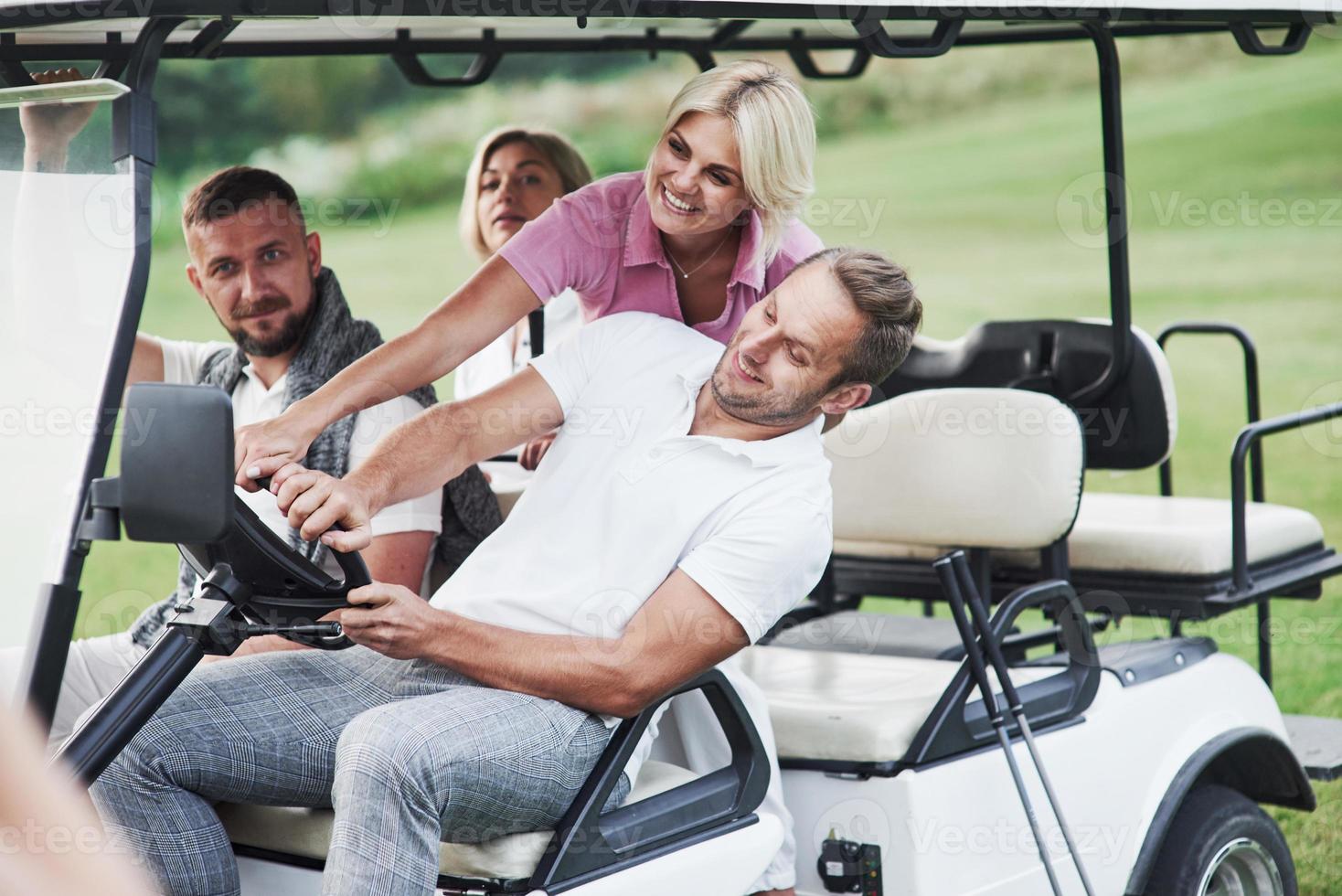 låt oss bli galna. familjevänner har kul att åka golfbil på fältet foto