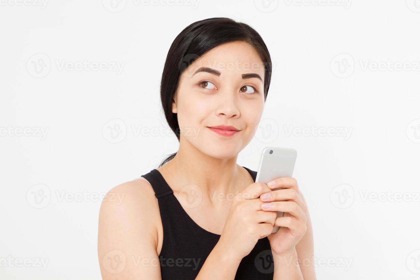 kvinna textar. närbild ung glad vacker asiatisk japansk kvinna. flicka tittar på mobiltelefon isolerad på vit bakgrund. positiva ansiktsuttryck mänskliga känslor. kopieringsutrymme. foto