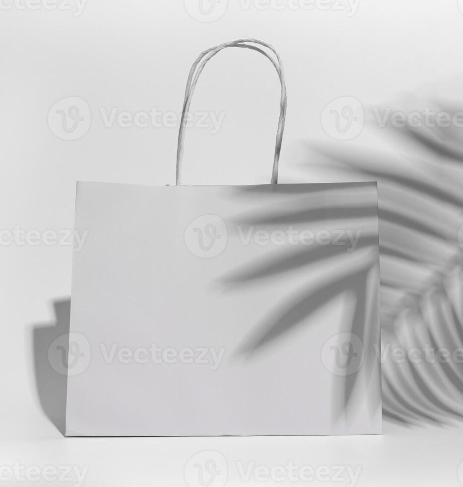 vit papper handla väska, packa med handtag, handflatan blad skugga foto