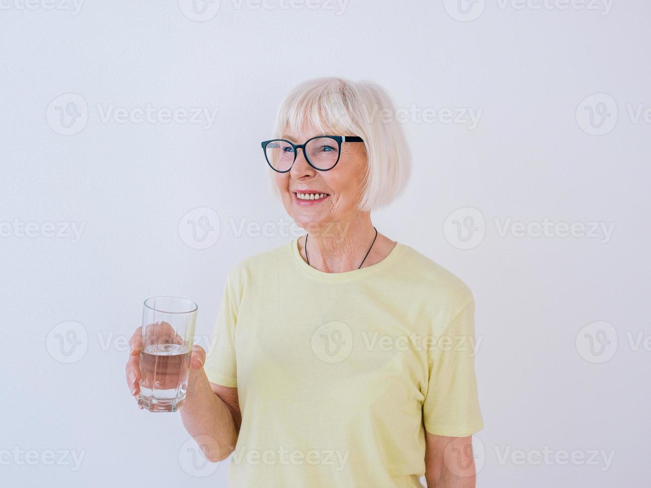 senior kvinna med glas vatten och dricksvatten. hälsosam livsstil, sport, anti-age koncept foto