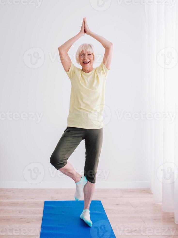 senior kvinna gör yoga inomhus. anti ålder, sport, yoga koncept foto