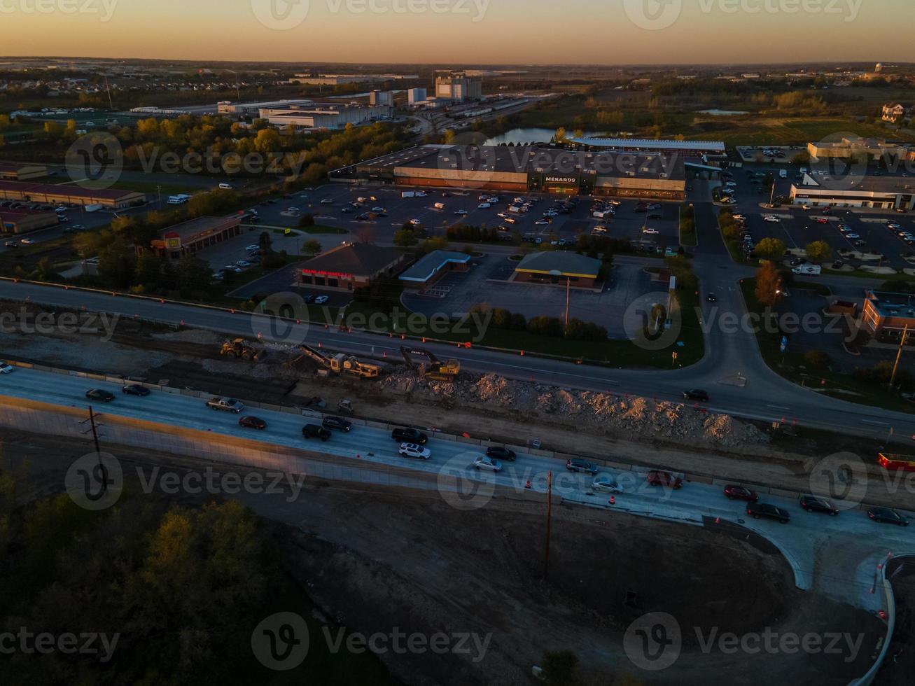 solnedgång utsikt över staden röda reflektioner utanför byggnaderna parkeringsplats tyst motorväg orange himmel trädkantade gator foto