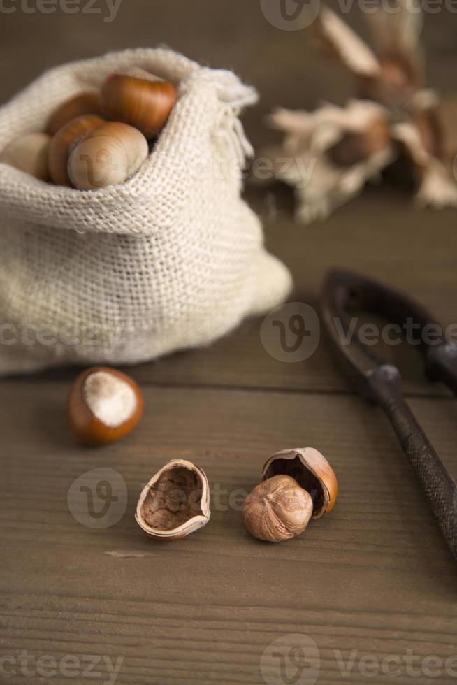 rustikt bord med hasselnötter och nötknäppare foto