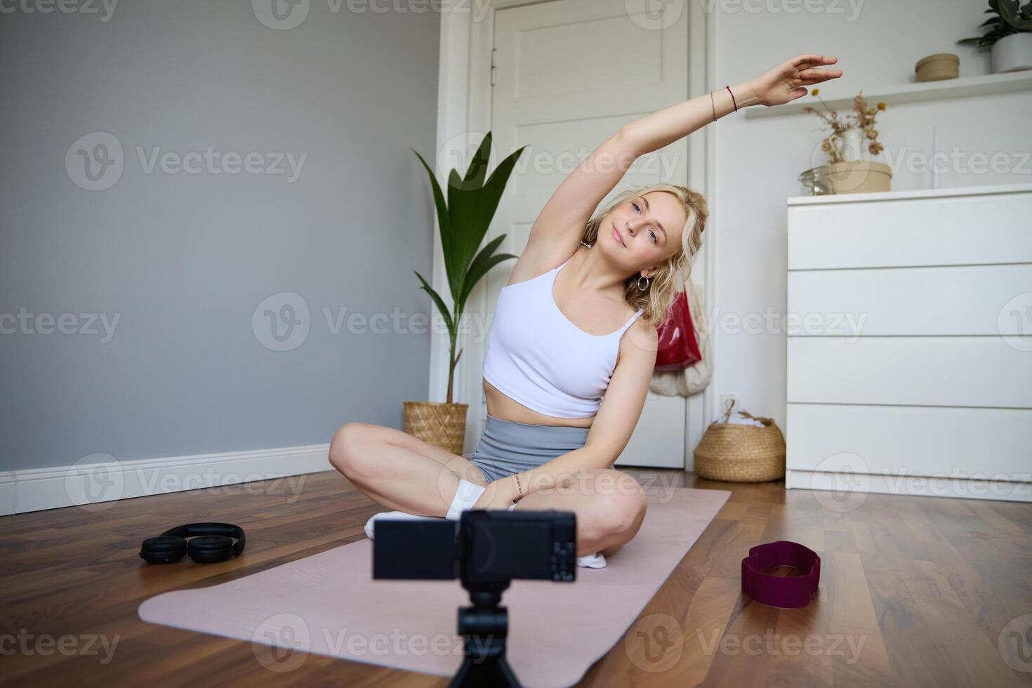 porträtt av ung bloggare, yoga innehåll skapare, som visar övningar, inspelning av själv arbetssätt ut på Hem på sudd matta foto