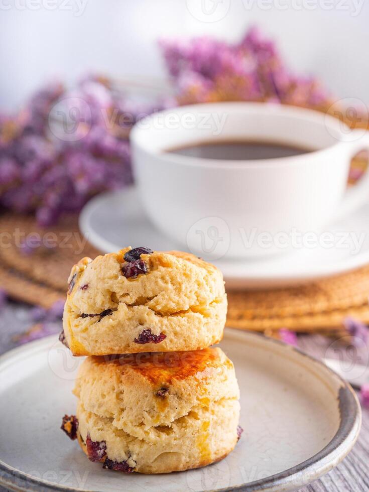 närbild av traditionell brittiskt scones på en tallrik med en vit kaffe kopp och blomma suddig bakgrund foto