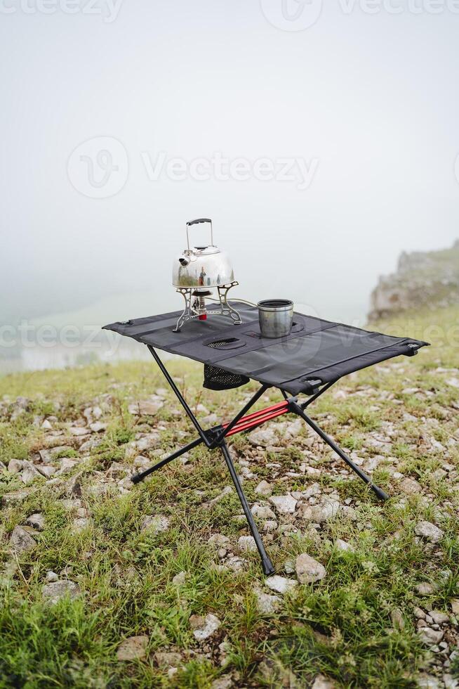 laga mat mat på en gas brännare på en vandra, turist redskap uppsättning av objekt för de kök, camping i de berg, en kopp av te, en små vattenkokare, vandring i de berg. foto