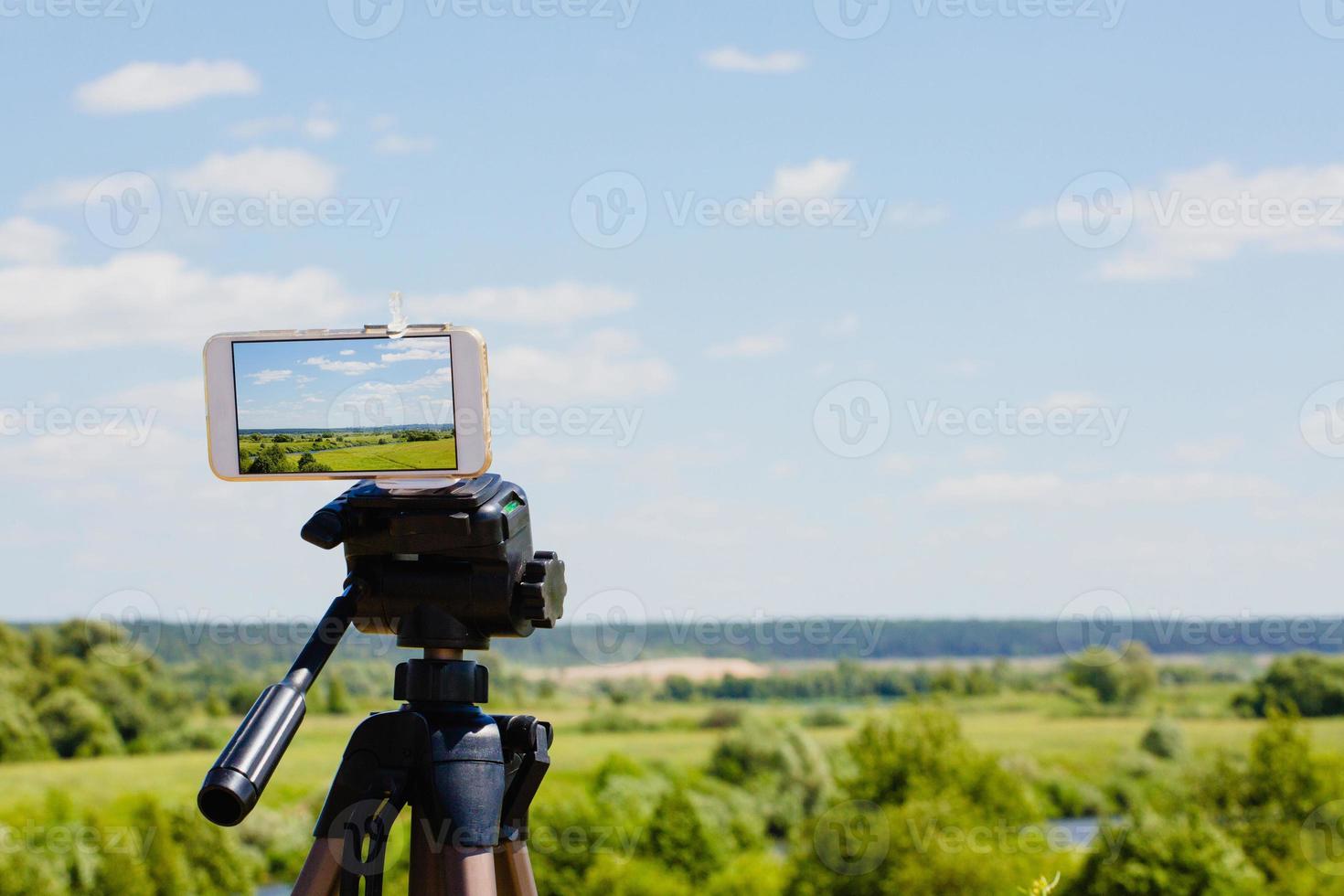 smartphone på stativ som fångar sommarlandskap foto