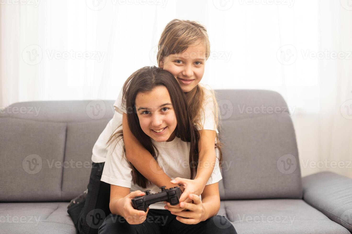 två mitten skola flickor på Hem spelar ett spännande video spel tillsammans. foto