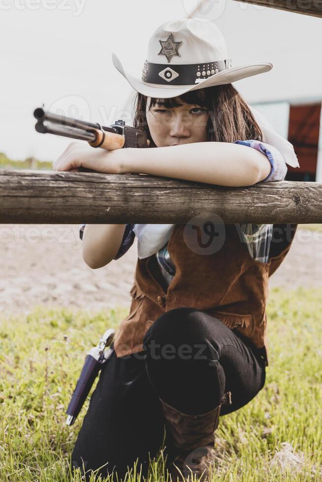 porträtt av en skön kinesisk kvinna cowgirl skytte med en vapen foto