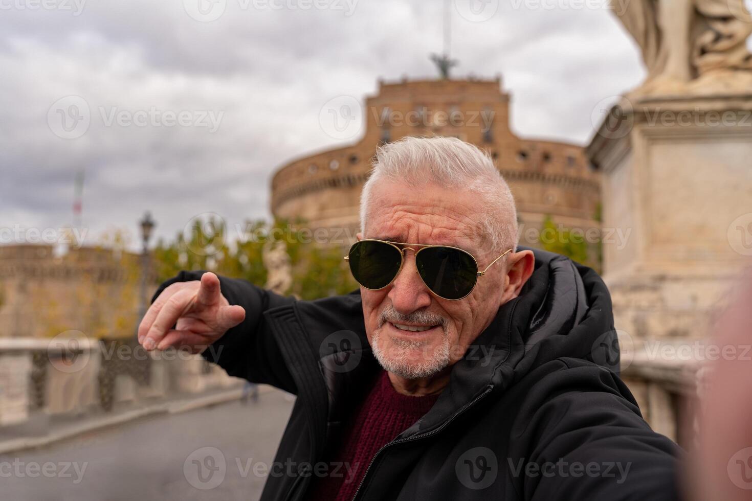 Lycklig mitten åldrig man på semester tar en selfie i främre av castel sant'angelo fästning i rom foto