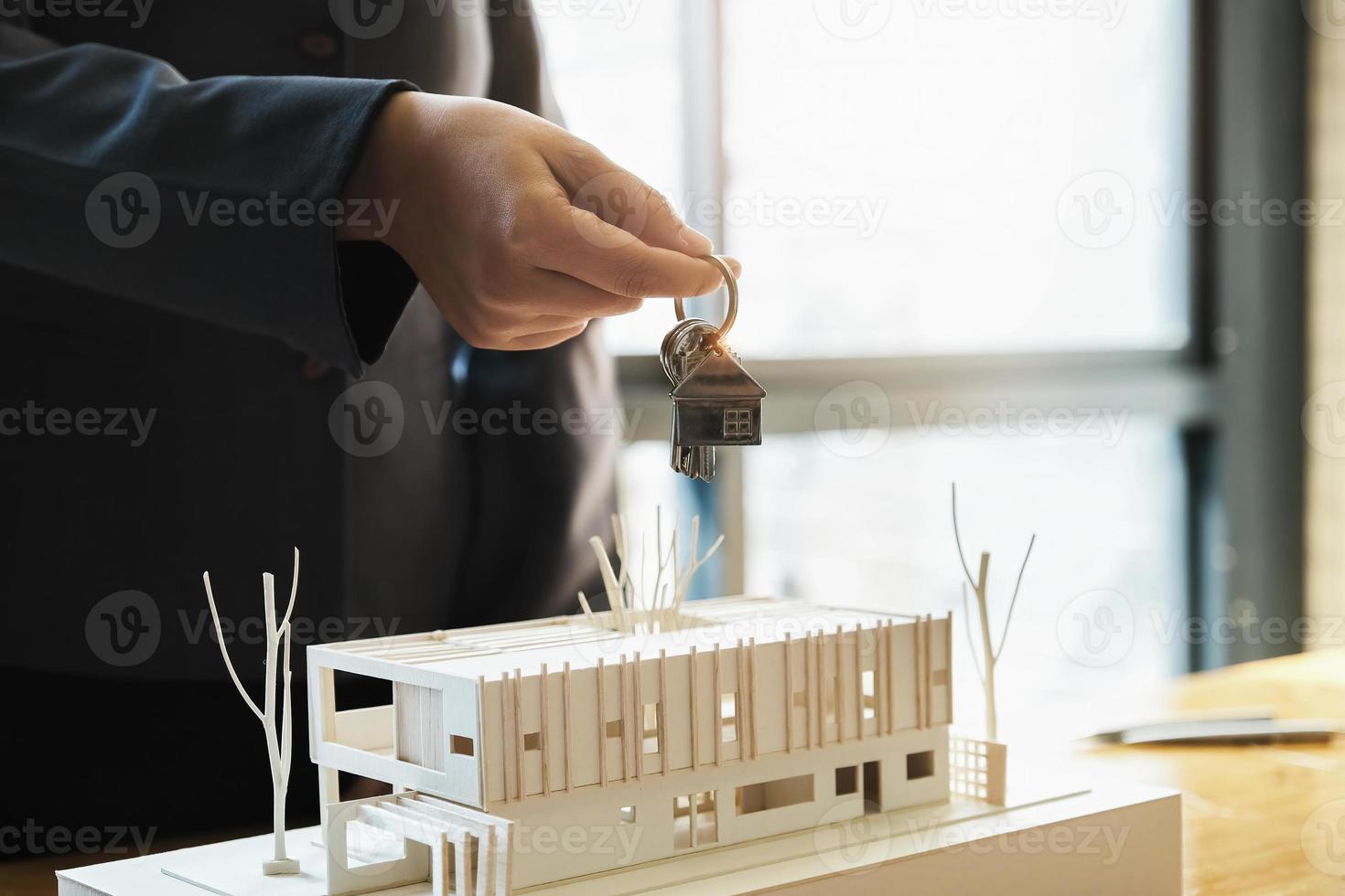 fastighetsmäklare går med på att köpa ett hem och ge nycklar till kunder på deras byråns kontor. konceptavtal. foto