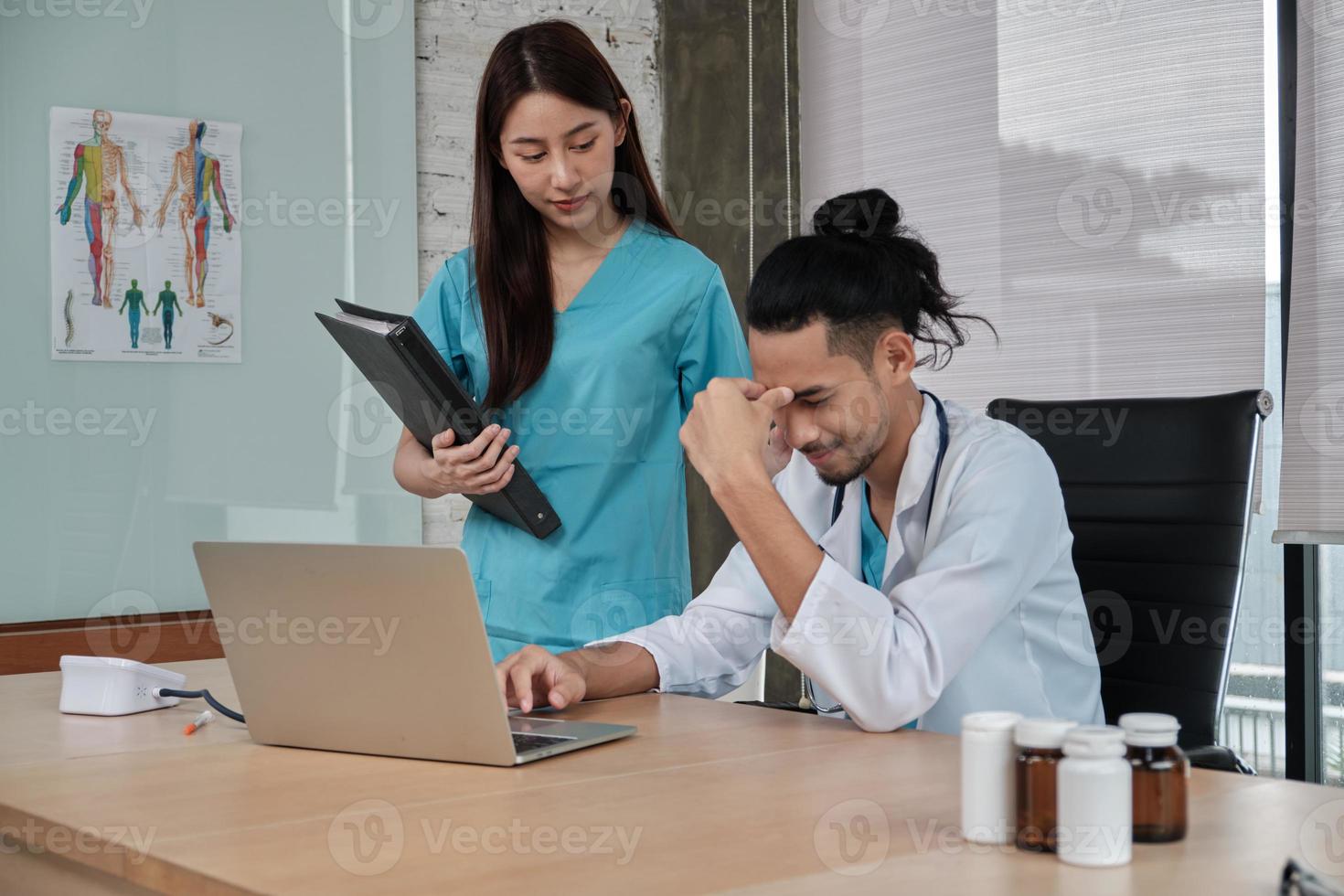 ung kvinnlig kollega uppmuntrar och tröstar manlig doktorpartner av asiatisk etnicitet som är ledsen och stressar på hälso- och sjukvårdsklinikens kontor på sjukhuset. foto