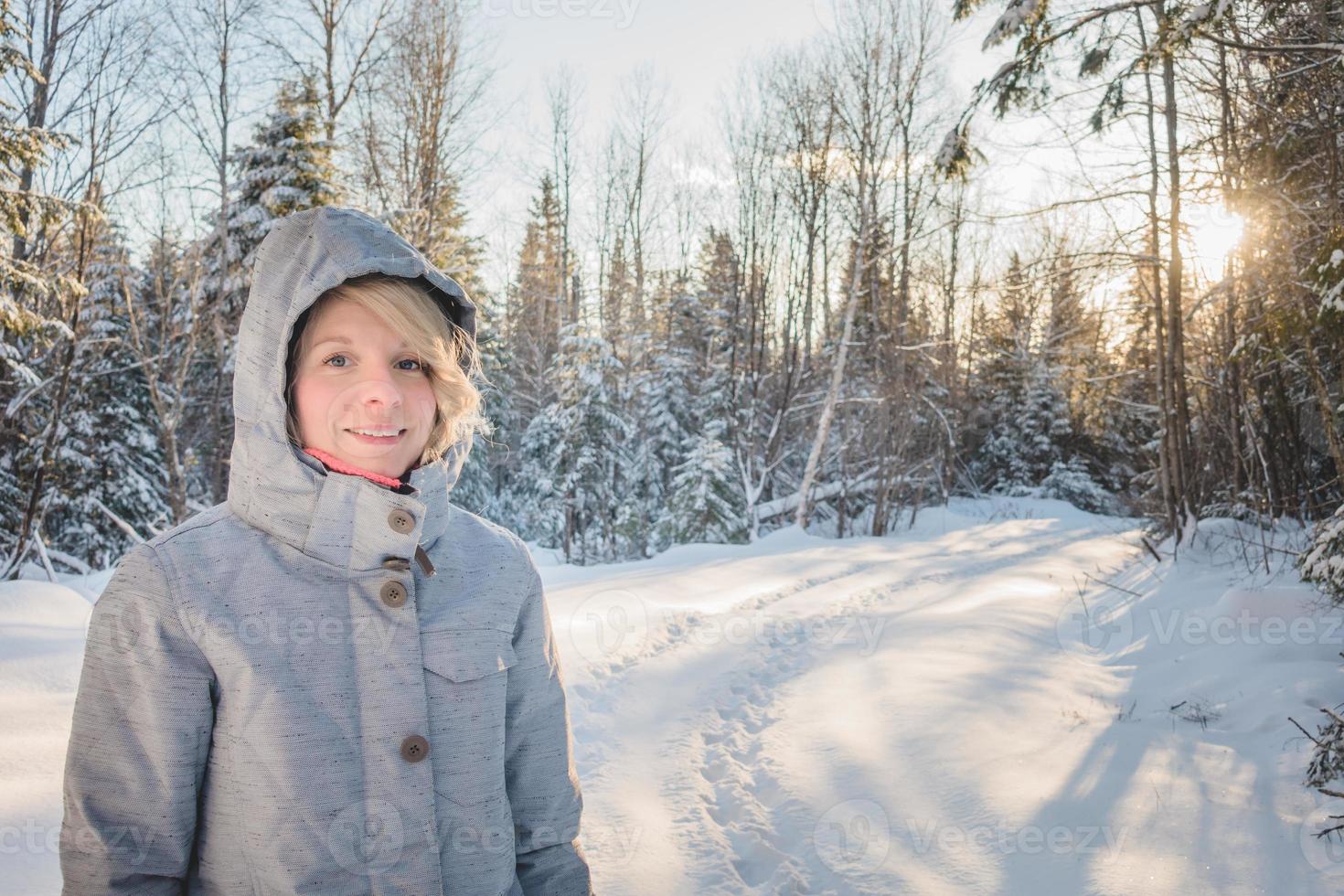 ung glad kvinna går ensam i skogen under vintern. foto