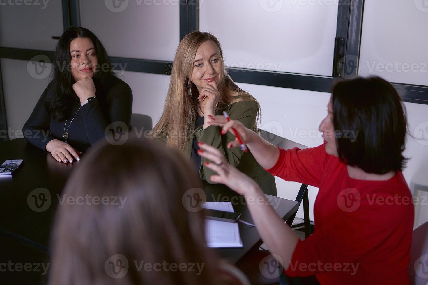 kvinna i en röd Tröja gester känslomässigt på en möte i de kontor foto
