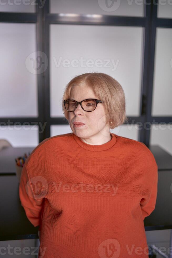 porträtt av en kvinna med en handikapp i ett orange Tröja och läder byxor i de kontor foto