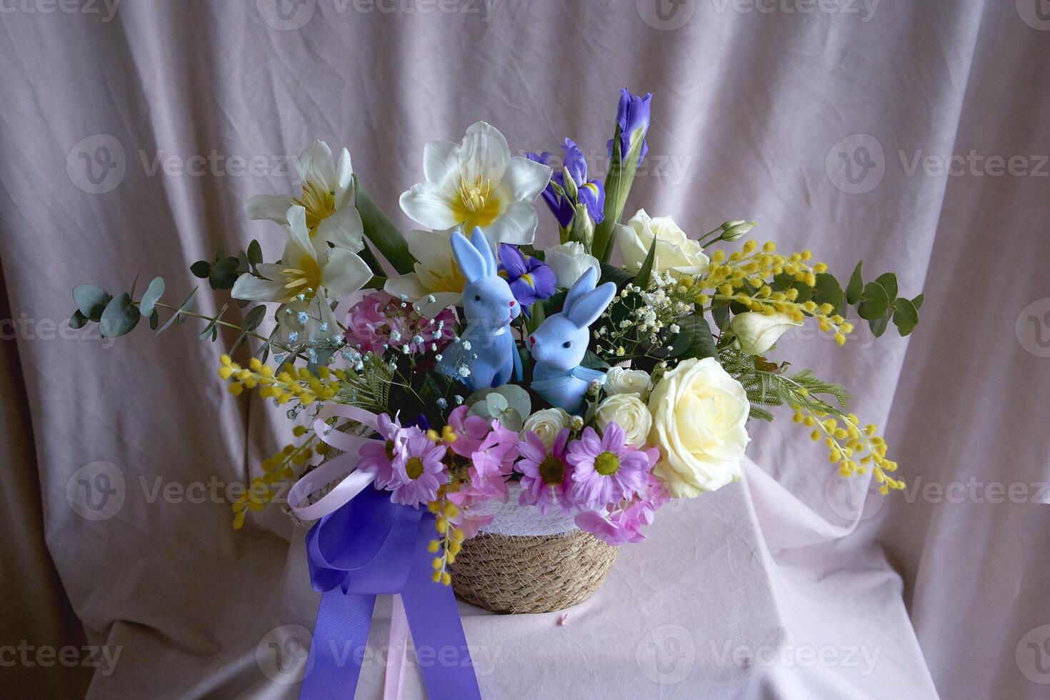 påsk blommig arrangemang med två blå påsk kaniner i en korg- korg foto