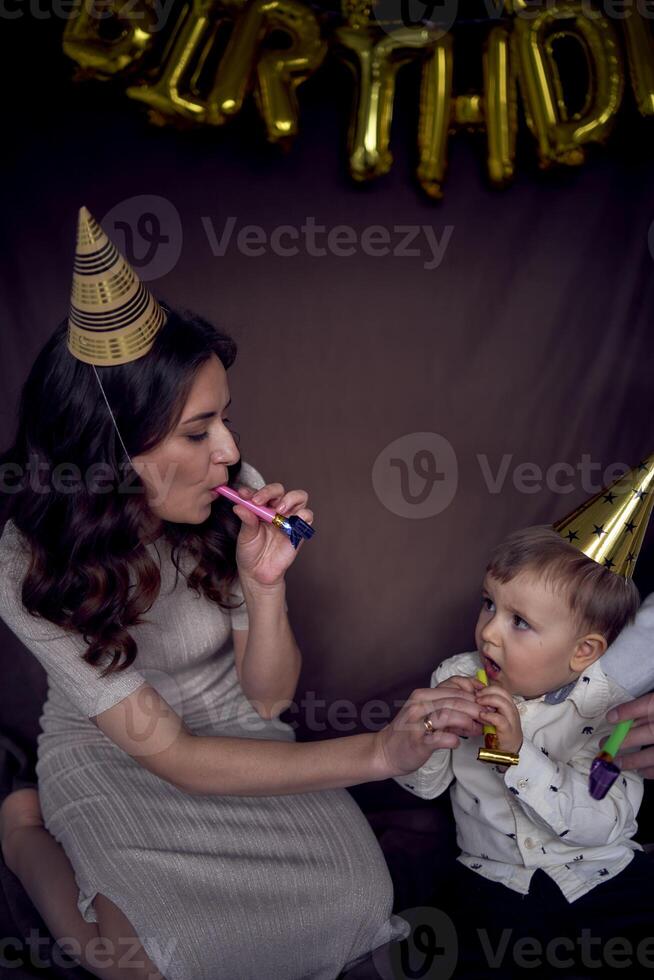 familj fira småbarns födelsedag bär fest hattar blåser rör foto