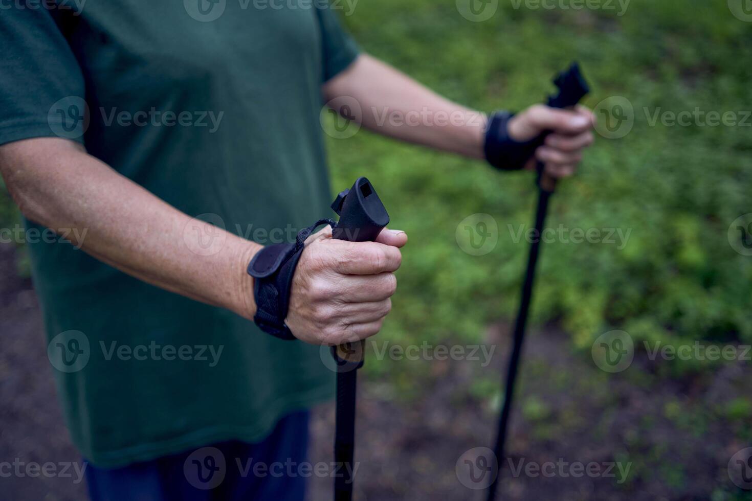 äldre kvinna är engagerad i nordic gående med pinnar i de vår skog foto