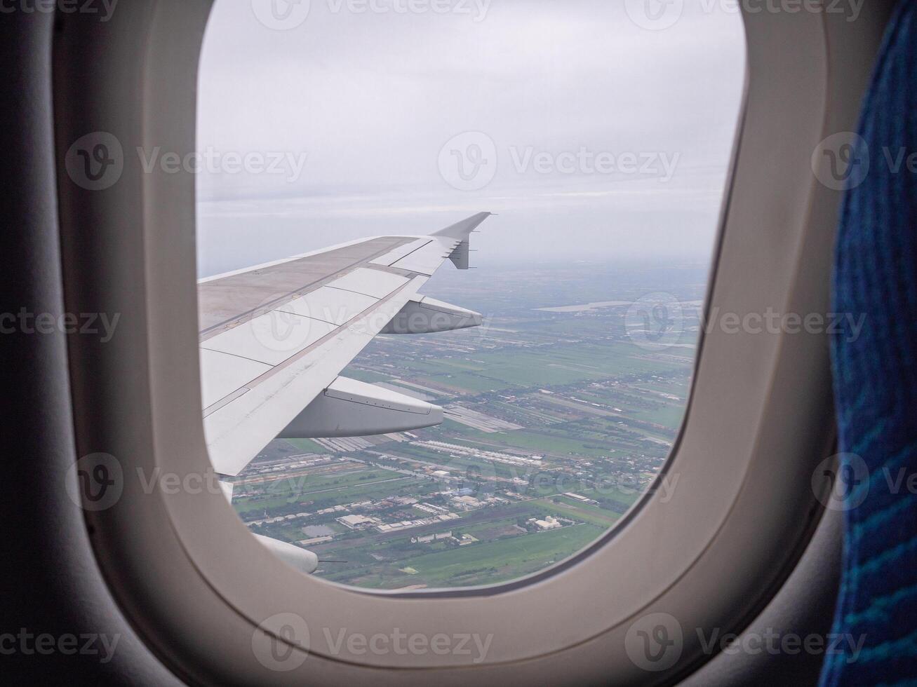 Flygfoto över land och moln sett genom flygplansfönster foto