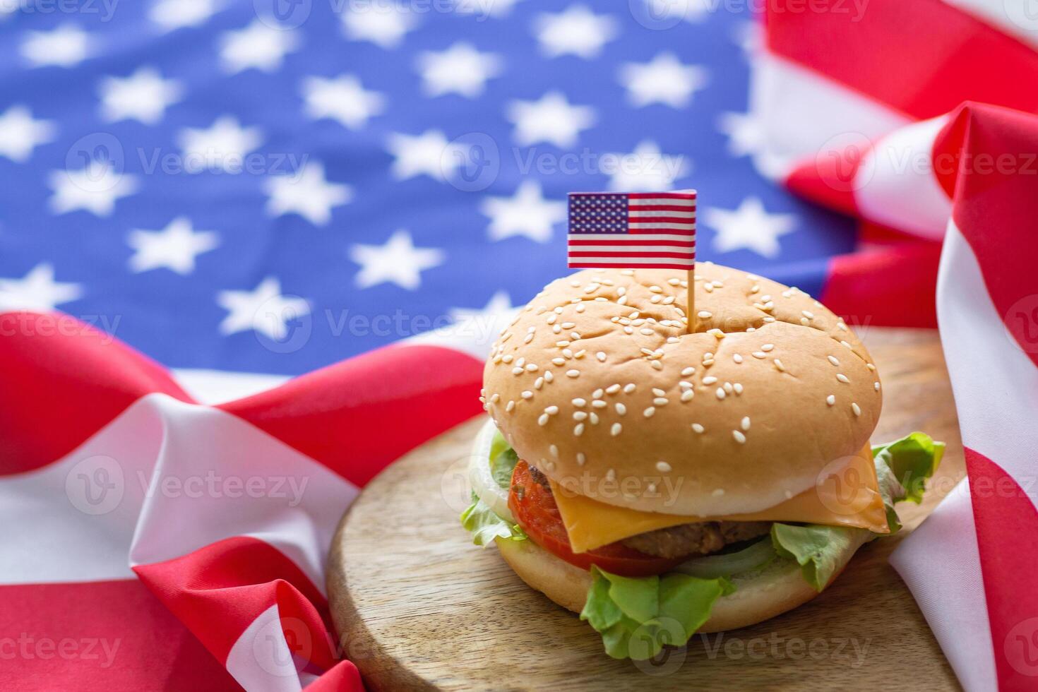 närbild av hemlagad två hamburgare med sallad och ost har ett amerikan flagga stift på de hamburgare placerad på en trä- hackning styrelse med ett amerikan flagga bakgrund på en trä- tabell foto