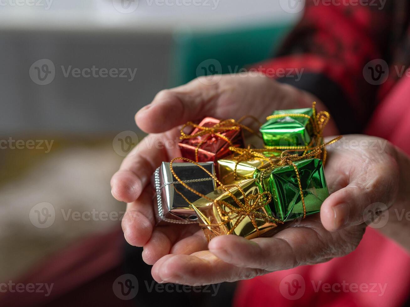 närbild av färgrik små gåva lådor i de händer av en senior kvinna inomhus. Plats för text. begrepp av festival och Semester foto