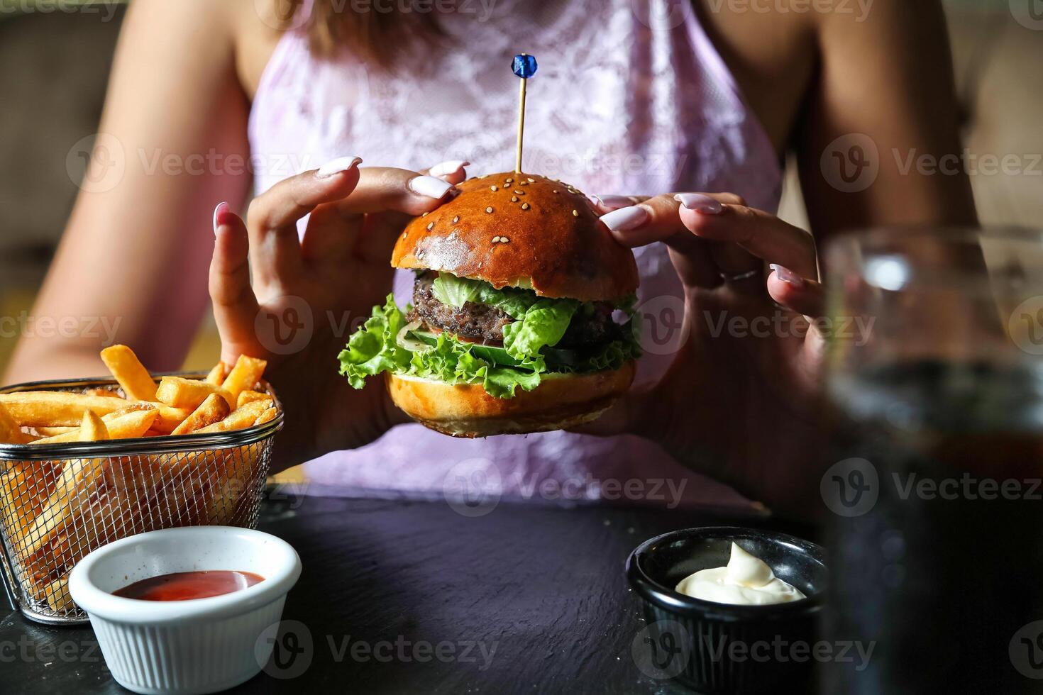 kvinna innehav en hamburgare och franska frites foto