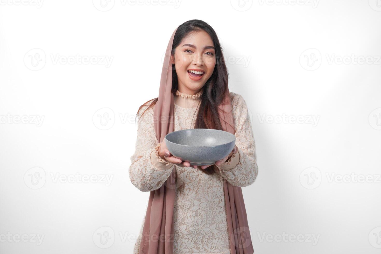 Lycklig asiatisk muslim kvinna innehav skål och bestick till äta efter fasta medan leende glatt på isolerat vit bakgrund. ramadan begrepp foto